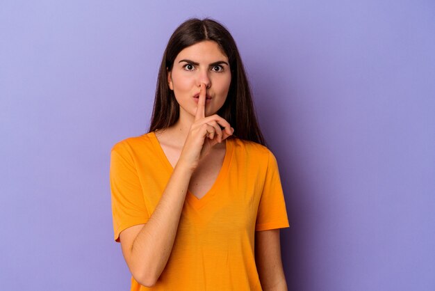 Foto giovane donna caucasica isolata su sfondo viola mantenendo un segreto o chiedendo silenzio.