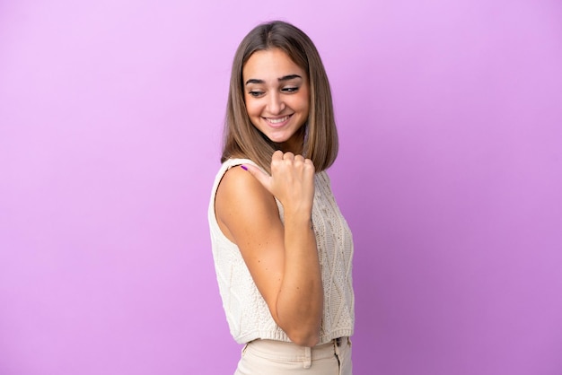 Young caucasian woman isolated on purple background pointing to the side to present a product