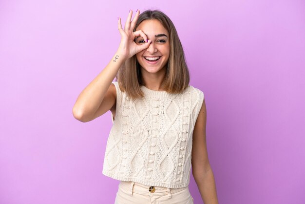 Young caucasian woman isolated on purple background showing ok sign with fingers