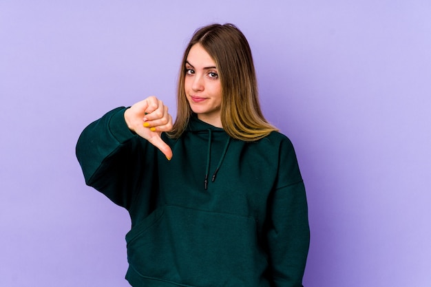 Young caucasian woman isolated on purple background showing thumb down, disappointment concept.