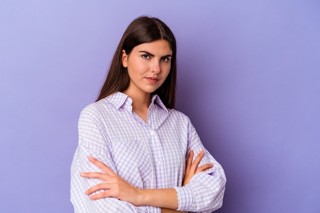 Young caucasian woman isolated on purple background suspicious, uncertain, examining you.