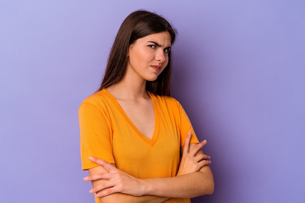 Young caucasian woman isolated on purple background suspicious, uncertain, examining you.