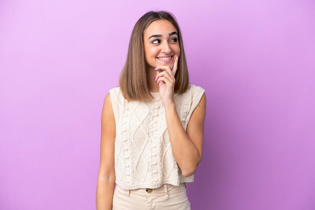 Young caucasian woman isolated on purple background thinking an idea while looking up