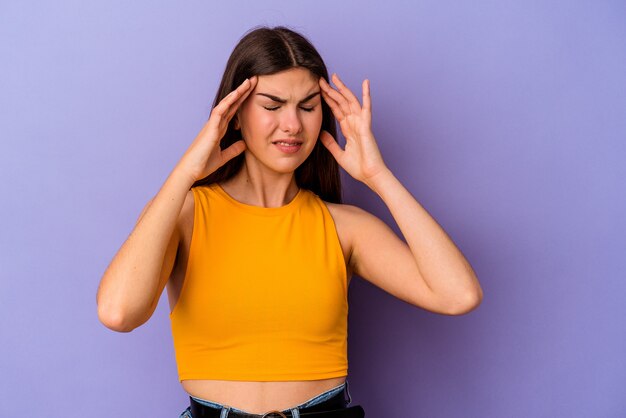 Young caucasian woman isolated on purple background touching temples and having headache.