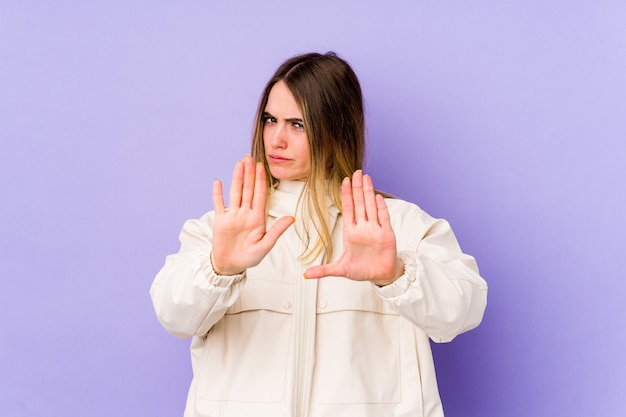 Young caucasian woman isolated on purple rejecting someone showing a gesture of disgust.