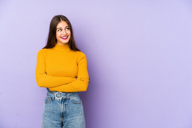 Young caucasian woman isolated on purple space smiling confident with crossed arms.