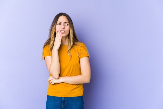 Young caucasian woman isolated on purple wall having a strong teeth pain, molar ache.