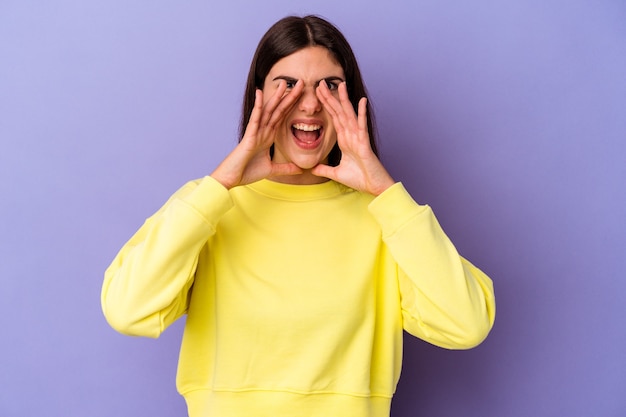 Young caucasian woman isolated on purple wall shouting excited to front