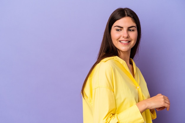 Young caucasian woman isolated on purple wall smiling confident with crossed arms.