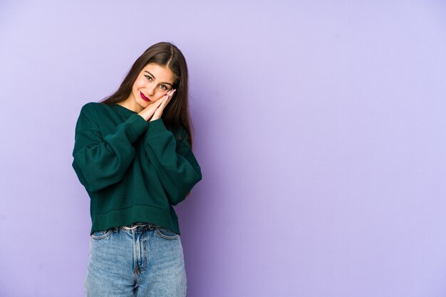 Young caucasian woman isolated on purple yawning showing a tired gesture covering mouth with hand.