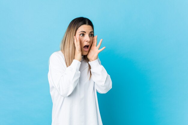 Young caucasian woman isolated shouts loud, keeps eyes opened and hands tense.