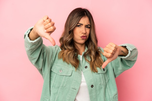 Young caucasian woman isolated showing thumb down and expressing dislike.