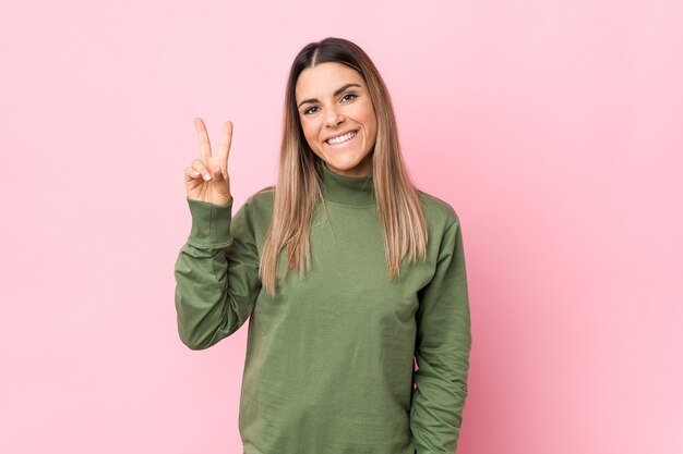 Young caucasian woman isolated showing victory sign and smiling broadly.