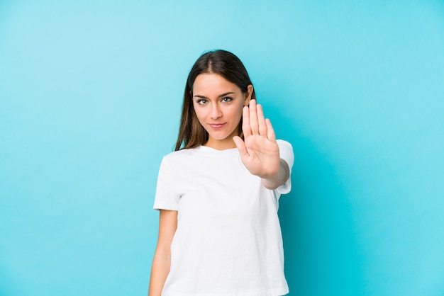 Young caucasian woman  isolated standing with outstretched hand showing stop sign, preventing you.