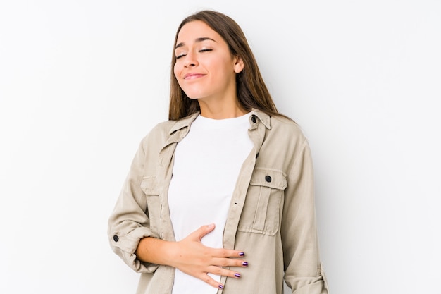 Young caucasian woman  isolated touches tummy, smiles gently, eating and satisfaction concept.