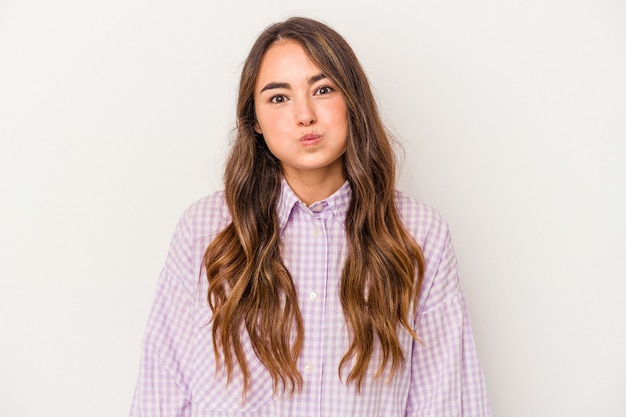 Young caucasian woman isolated on white background blows cheeks, has tired expression. Facial expression concept.