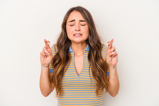 Young caucasian woman isolated on white background crossing fingers for having luck