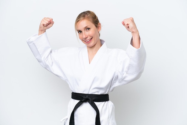 Young caucasian woman isolated on white background doing karate and making strong gesture