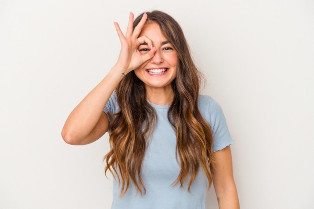 young caucasian woman isolated on white background excited keeping ok gesture on eye.