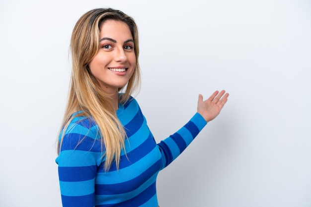 Young caucasian woman isolated on white background extending hands to the side for inviting to come