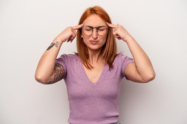 Young caucasian woman isolated on white background focused on a task keeping forefingers pointing head