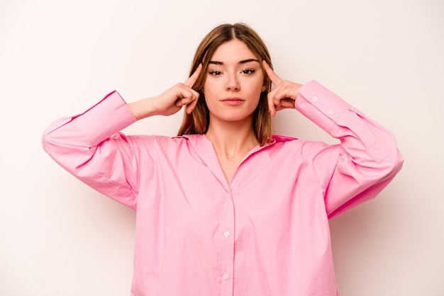 Young caucasian woman isolated on white background focused on a task keeping forefingers pointing head