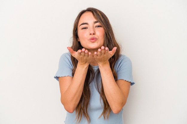 Young caucasian woman isolated on white background folding lips and holding palms to send air kiss.