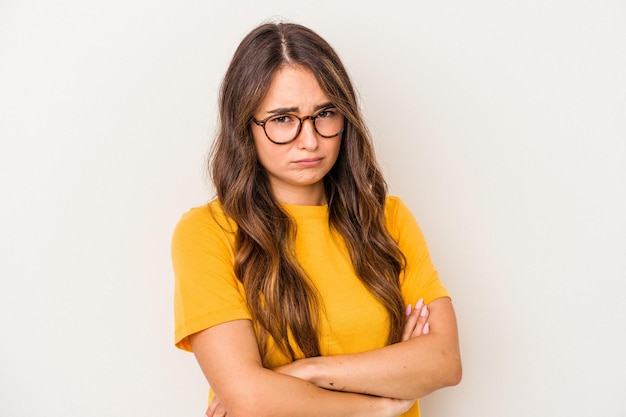 Young caucasian woman isolated on white background frowning face in displeasure, keeps arms folded.