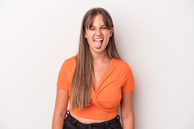 Young caucasian woman isolated on white background funny and friendly sticking out tongue.