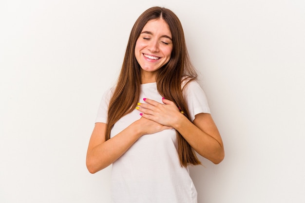 Young caucasian woman isolated on white background has friendly expression, pressing palm to chest. Love concept.