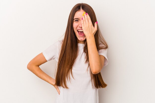 Young caucasian woman isolated on white background having fun covering half of face with palm.