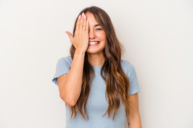 Young caucasian woman isolated on white background having fun covering half of face with palm.