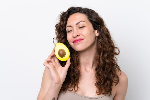 Young caucasian woman isolated on white background holding an avocado Close up portrait