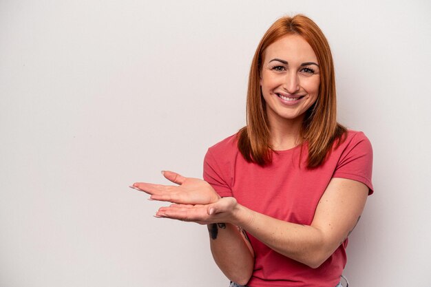 Young caucasian woman isolated on white background holding a copy space on a palm.