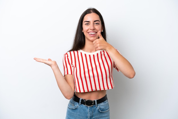 Young caucasian woman isolated on white background holding copyspace imaginary on the palm to insert an ad and with thumbs up