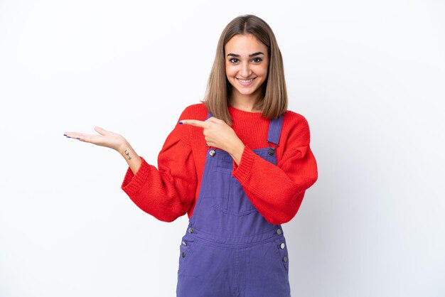 Young caucasian woman isolated on white background holding copyspace imaginary on the palm to insert an ad