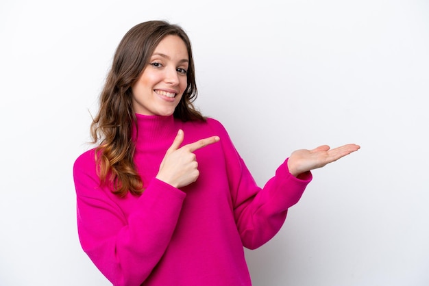 Young caucasian woman isolated on white background holding copyspace imaginary on the palm to insert an ad