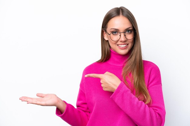 Young caucasian woman isolated on white background holding copyspace imaginary on the palm to insert an ad