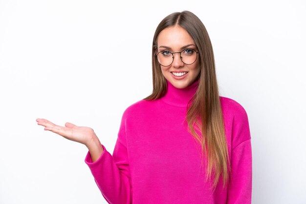 Young caucasian woman isolated on white background holding copyspace imaginary on the palm to insert an ad