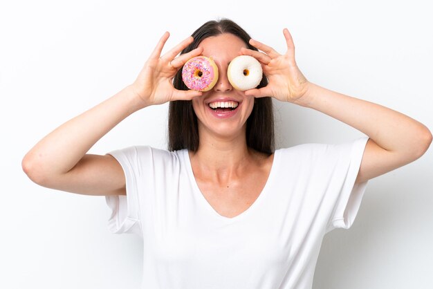 Young caucasian woman isolated on white background holding donuts in eyes