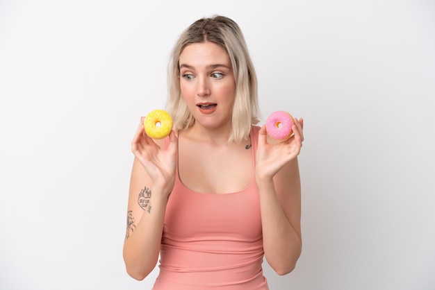 Young caucasian woman isolated on white background holding donuts with happy expression