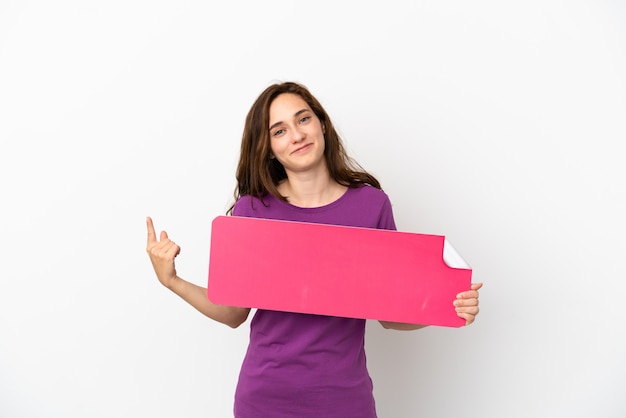 Young caucasian woman isolated on white background holding an empty placard and doing coming gesture