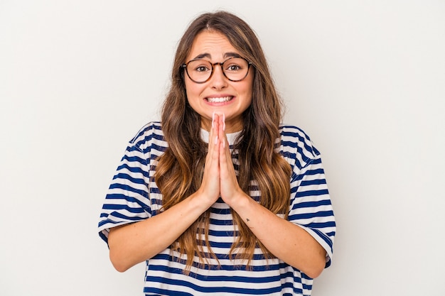 Young caucasian woman isolated on white background holding hands in pray near mouth, feels confident.