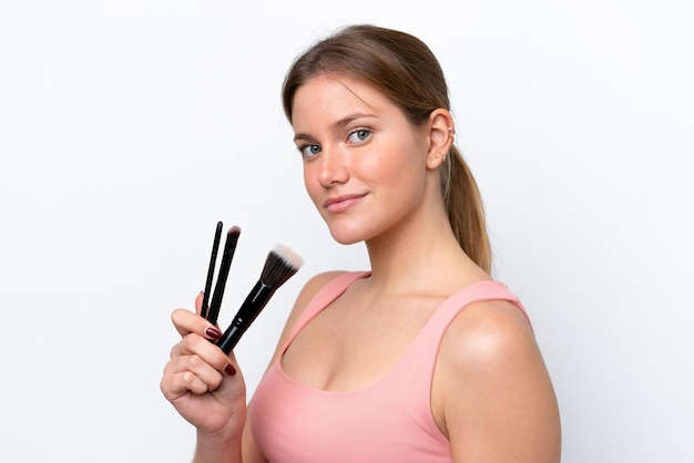 Young caucasian woman isolated on white background holding makeup brush