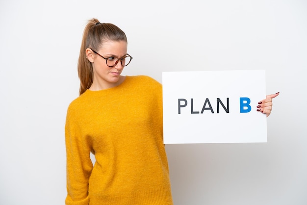 Young caucasian woman isolated on white background holding a placard with the message PLAN B with sad expression