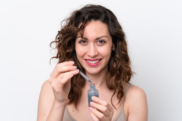 Young caucasian woman isolated on white background holding a serum Close up portrait