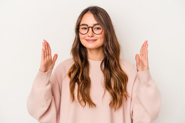 Young caucasian woman isolated on white background holding something little with forefingers, smiling and confident.