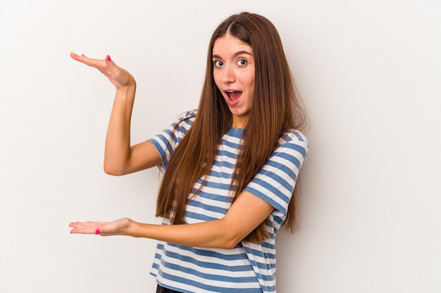 Young caucasian woman isolated on white background holding something with both hands, product presentation.