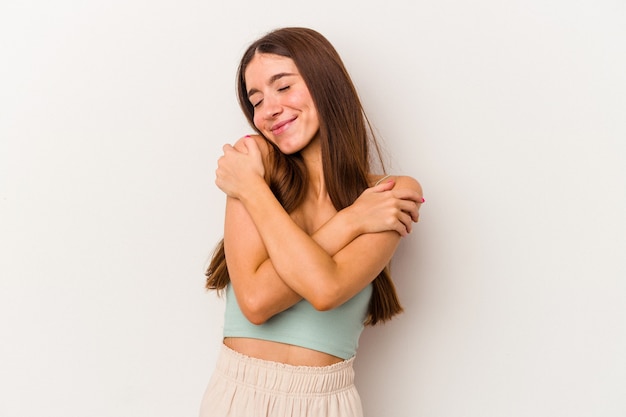 Young caucasian woman isolated on white background hugs, smiling carefree and happy.