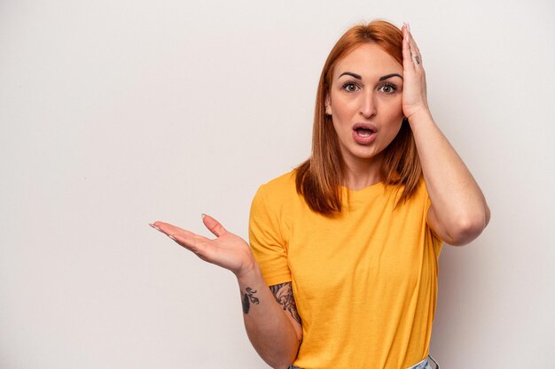 Young caucasian woman isolated on white background impressed holding copy space on palm.